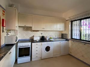 cocina con armarios blancos y lavadora en Beautiful Villa with terrace & garden, en Ferragudo