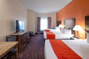a hotel room with two beds and a flat screen tv at Home Away Kitchen Suites Enid in Enid