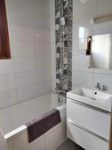 a white bathroom with a tub and a sink at Le clair logis in Sixt