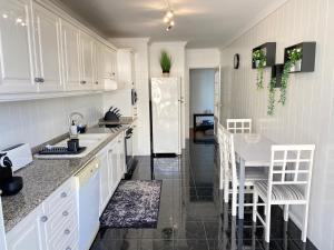 a kitchen with white cabinets and a white refrigerator at OndasDaVagueira - T2 em condomínio com piscina in Gafanha da Boa Hora