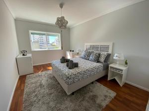 a white bedroom with a bed and a rug at OndasDaVagueira - T2 em condomínio com piscina in Gafanha da Boa Hora
