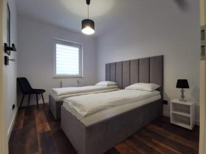 a bedroom with two beds and a chair and a window at Apartamenty Mazurska Bryza nad Iławką in Iława