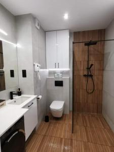 a bathroom with a toilet and a shower in it at Apartamenty Mazurska Bryza nad Iławką in Iława