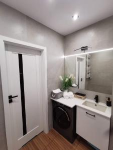 a bathroom with a washing machine and a sink at Apartamenty Mazurska Bryza nad Iławką in Iława +16 photos