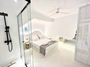 una camera bianca con un letto e una porta in vetro di Ananke with Shared Pool a Mykonos Città