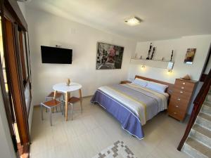 een slaapkamer met een bed en een tafel en een televisie bij Benalmadena ALOHA PLAYA SEA VIEW LOFT in Benalmádena