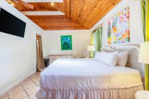 基韋斯特的住宿－Key Lime Calypso，卧室设有白色的床和木制天花板。