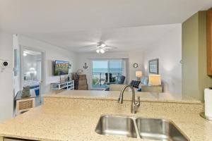 a kitchen with a sink and a living room at Windjammer 209 in St. Augustine