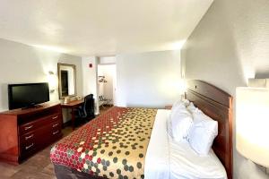 a hotel room with a bed and a desk and a television at Red Carpet Inn Philadelphia Airport in Lester