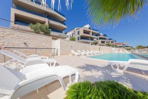 a resort with a swimming pool and white lounge chairs at Resort Banjole - apartman Indigo in Banjole