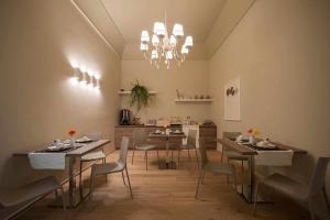 una sala da pranzo con tavoli, sedie e lampadario a braccio di Antica Dimora Luxury Rooms a Barletta