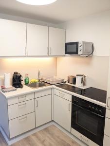 a kitchen with white cabinets and a sink and a microwave at WiLDBADFERiEN punkt DE in Bad Wildbad