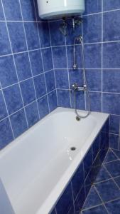 W wyłożonej niebieskimi kafelkami łazience znajduje się wanna z prysznicem. w obiekcie House of the Rising Sun w mieście Bosanska Gradiška