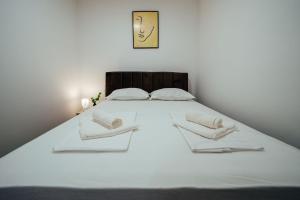 a white bed with two white pillows and a clock at Apartman Biokovo in Imotski