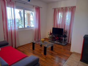 uma sala de estar com uma mesa e uma televisão e cortinas vermelhas em Apartman Luka em Blato