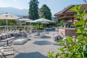 a patio with white couches and umbrellas at Residence Les Chataigniers in Saint-Jorioz