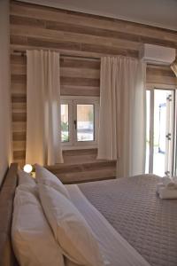 a bedroom with a large bed with white sheets and windows at Porfyra Suite & Spa 1 in Skala