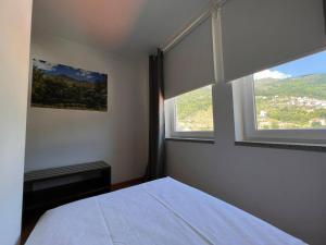 a bedroom with a white bed and two windows at Vale do Zêzere Hotel in Manteigas