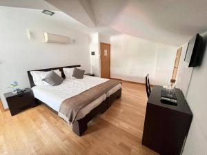 um quarto com uma cama e uma escrivaninha com uma televisão em Vale do Zêzere Hotel em Manteigas mais 37 fotografias