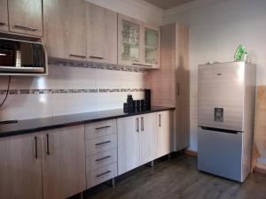 una cucina con armadi in legno e frigorifero in acciaio inossidabile di G Guest House a King Williamʼs Town