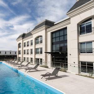 a building with a row of chairs next to a swimming pool at Apart France - Con gim, piscina y estacionamiento in Río Cuarto