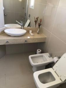 a bathroom with a sink and a toilet and a mirror at Apart France - Con gim, piscina y estacionamiento in Río Cuarto