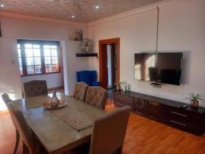 una sala da pranzo con tavolo e TV di G Guest House a King Williamʼs Town