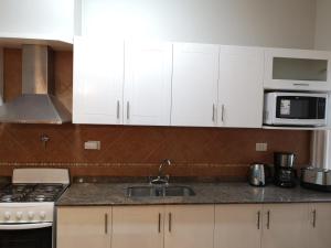 una cocina con armarios blancos y fregadero en Precioso Departamento - Excelente ubicación en Mendoza