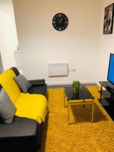 a living room with a couch and a clock on the wall at City Blessed Apartment 1 with free parking in North Shields