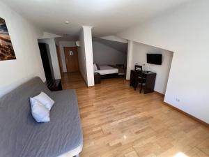 ein Wohnzimmer mit einem Bett und ein Zimmer mit einem Schreibtisch in der Unterkunft Vale do Zêzere Hotel in Manteigas