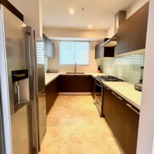 a kitchen with brown cabinets and a large window at Espectacular Apartamento Familiar con Piscina en Panamá 