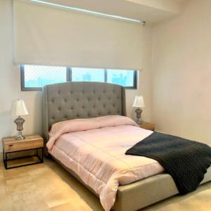 a bedroom with a bed with pink sheets and a window at Espectacular Apartamento Familiar con Piscina en Panamá 