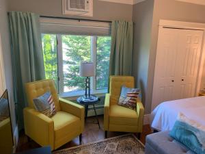 a bedroom with two chairs and a bed and a window at White Sails Inn in Kennebunk