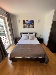 a bedroom with a large bed and a large window at Vale do Zêzere Hotel in Manteigas