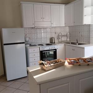 a kitchen with white cabinets and a white refrigerator at Meteora Casa Di Stella in Kalabaka