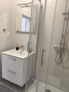 a white bathroom with a sink and a shower at Apartments Erenda in Fuškulin