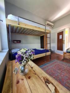 Milingona City Center Hostel في تيرانا: غرفة بسريرين بطابقين وطاولة مع ورد