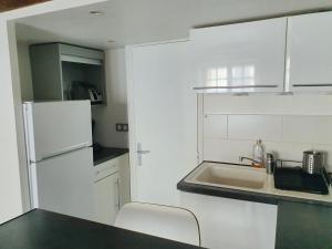 biała kuchnia ze zlewem i lodówką w obiekcie EXIGEHOME-Studio Cosy à 2 pas du Chateau de Versailles w Wersalu +4 zdjęcia