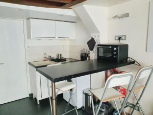kuchnia z blatem z kuchenką mikrofalową i krzesłami w obiekcie EXIGEHOME-Studio Cosy à 2 pas du Chateau de Versailles w Wersalu