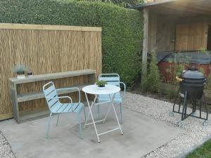 un patio con mesa, sillas y parrilla en Sea You Soon privé kamer met jacuzzi en sauna, en Bredene