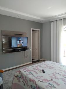 una camera da letto con un letto e una TV a parete di Casa de novela , Sol e piscina a Cachoeiras de Macacu