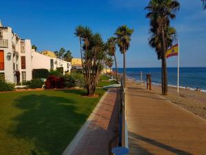 a sidewalk next to the beach with palm trees at Butiplaya apartament in La Cala de Mijas