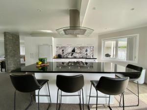 a kitchen with a black counter and black chairs at The Great Escape, Luxury Waterfront, HotTub in Whitianga