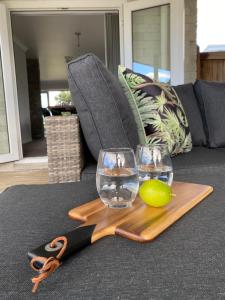 a wooden cutting board with two glasses and a pair of scissors at The Great Escape, Luxury Waterfront, HotTub in Whitianga
