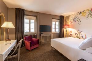 a hotel room with a large bed and a red chair at Best Western Plus d'Europe et d'Angleterre in Mâcon +145 photos