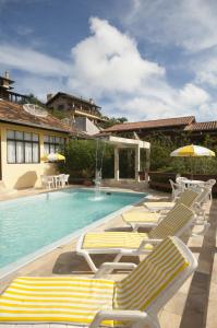 a group of lounge chairs and a swimming pool at Pousada Cabanas Porto Belo in Bombinhas