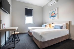 a bedroom with a bed, desk, chair and window at Nightcap at Federal Hotel Mt Gambier in Mount Gambier