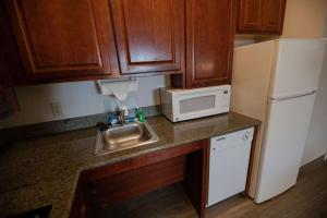 a kitchen with a sink and a microwave and a refrigerator at Sonesta ES Suites Baton Rouge University at Southgate in Baton Rouge