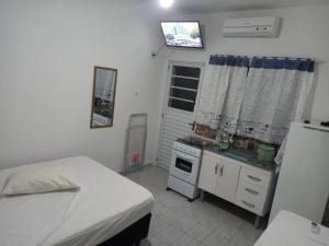 ein Zimmer mit einem Bett und einer Küche mit Kühlschrank in der Unterkunft Chalé do Tio Beto - Caraguatatuba in Caraguatatuba