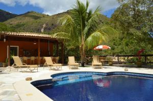 - une piscine avec des chaises et un parasol à côté d'une maison dans l'établissement Artesanal Gourmet e Pousada, à Posse